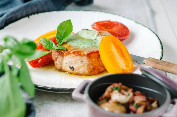 Kemiğin üzerinde yeşil tereyağlı domuz filetosu. Fırında domates, konserve sarımsak ve domuz pastırmalı kızarmış patates..