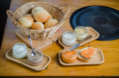 Çörek, humus, börek, sebze ve peynir dolu sepet kavanozlara yayılır. Çeşitli soslar, mezeler ve ahşap masa manzaralı ekmek ekmeği.