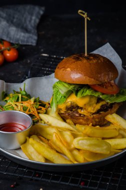 Siyah arka planda ahşap tahtada sığır burger ve patates kızartması. Yakın plan. Restoranda servis.