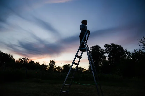 silhouette of a boy on the stairs against the background of the night sky