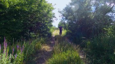 Bir adam ağaçların yanında bisiklet sürüyor.