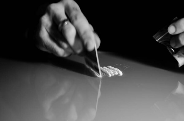 Белый человек делит кокаин на полоски, так что он может нюхать его позже. Концепция наркотиков, наркомании. Высокое качество фото