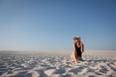 Güzel şapkalı, kumda bir kız.