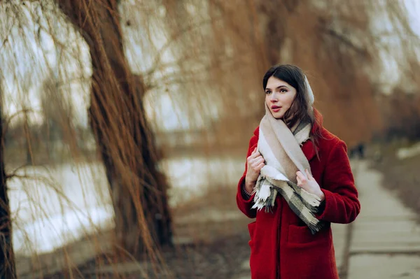 beautiful young woman in a white coat and scarf posing in the autumn park