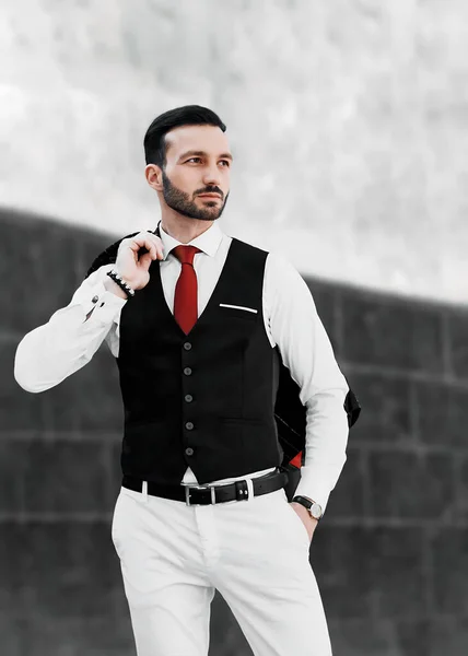 Siyah takım elbiseli, beyaz pantolonlu şık, genç ve sakallı bir adam. Sokakta durup başka tarafa bakıyor. moda konsepti. 