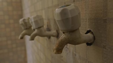 Su, banyodaki eski plastik musluktan damlıyor.