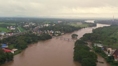 An aerial view of a small town where the river is flooding under a small rail bridge
