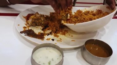 Man eating Indian popular food chicken biriyani served with curd and curry. The most popular Indian cuisine chicken is prepared using rice, chicken and tasty spices.