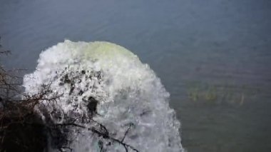 Yağmur mevsiminde göle doğru akan büyük metal borudan akan suyun ya da göldeki suyu dolduran suyun yakın görüntüsü.