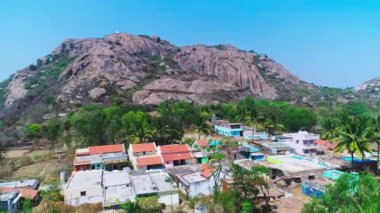 Hindistan 'da yaz aylarında uzun yıllardan korunan büyük kaya dağının altındaki küçük bir köyün havadan görünüşü.