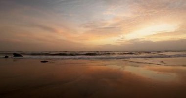 Gün batımında turuncu renkli güzel bir sahil manzarası ve yaz zamanı sakin dalgalar.