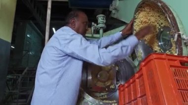 Bangalore, Hindistan-5 Nisan 2016: Sabun / konveyör makinesinin makine / üretiminden ham sabunu temizleyen yaşlı bir adam