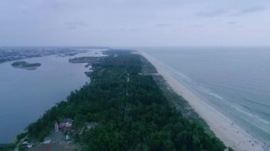 Ağaçlarla ve yollarla bölünmüş güzel sahil ve nehir havası. Kuşların bakış açısı. Güzel gün batımı zamanı Denizde
