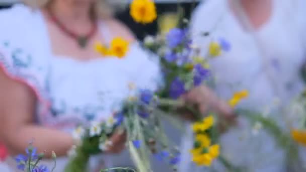 Una chica teje una corona de flores silvestres — Vídeos de Stock