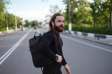 Siyah sakallı genç adam otobandan karşıya geçiyor..