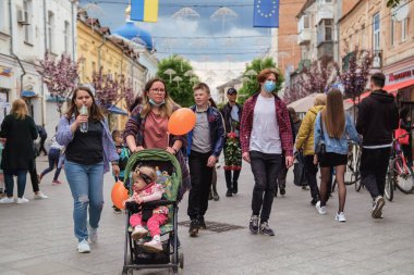 Zhytomyr, Ukraine - May 15, 2021: crowd of people at central street of the town enjoy the walk at dramatic sky background