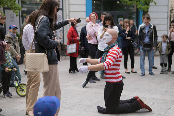 Zhytomyr, Ukraine - May 15, 2021: Professional mime artist performing different emotions and interacts with people. Man with a hat begging for money