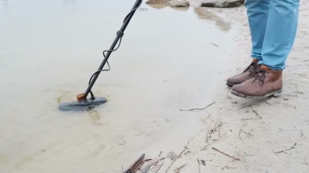 Людина з металошукачем шукає монети під водою . — стокове відео