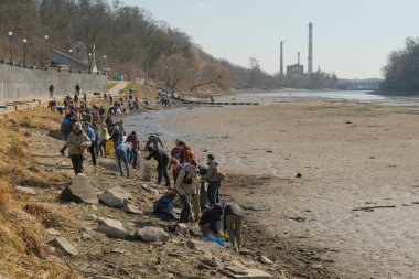 Zhytomyr, Ukrayna - 24 Mart 2022: Yüzlerce gönüllü nehir kenarındaki çöpleri temizlerken su barajını indiriyor. Ukrayna ve Rusya arasındaki savaş sırasında insanlar daha aktif hale geldi.