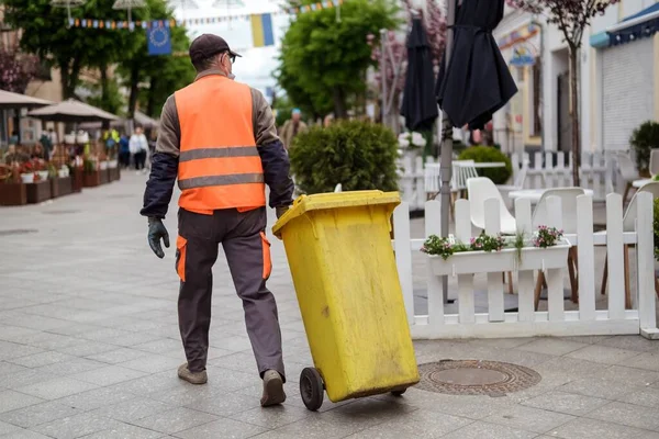 穿着橙色制服 头戴黄色垃圾桶的街头工人看门人 免版税图库照片