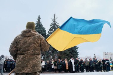 Soldier in camouflage holding and waving ukrainian flag at independence day of Ukraine.
