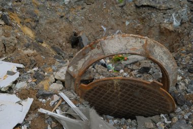 2022 yılında Ukrayna 'nın Kharkiv bölgesinde bir Rus topunun patlaması sonucu oluşan bir delik. Bombardıman kraterinde tahrip edilmiş kanalizasyon kapağı.