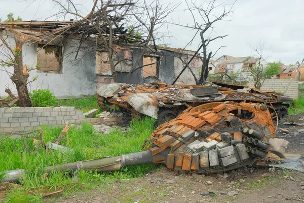 Russian battle tank remains with torn down gun turret which was destroyed during Russian invasion of Ukraine. Russian tank was hiding in the yard of ukrainian village.