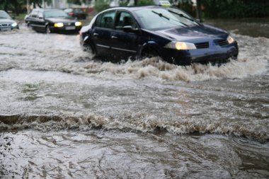 Şiddetli yağmur ve sağanak yağış sırasında sel basmış şehir caddesinde araba trafiği. Felaket seli, sel. Su akışı