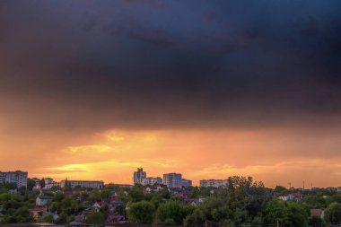 Renkli akşam gökyüzü kırmızı, turuncu, mavi, gri, pembe renkler ve binaların siluetleriyle boyanmış.