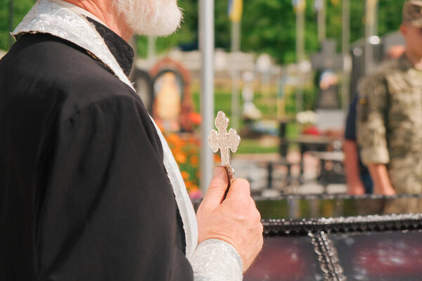 Christian priest blessing with cross during funeral. Last farewell to person.