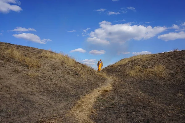 Beyaz gömlekli bir adam dağlarda yürüyor..