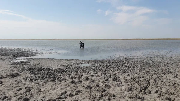 Bir erkek ve bir kadın cesedi nehir kıyısına terapi amaçlı çamurla süpürüyor..