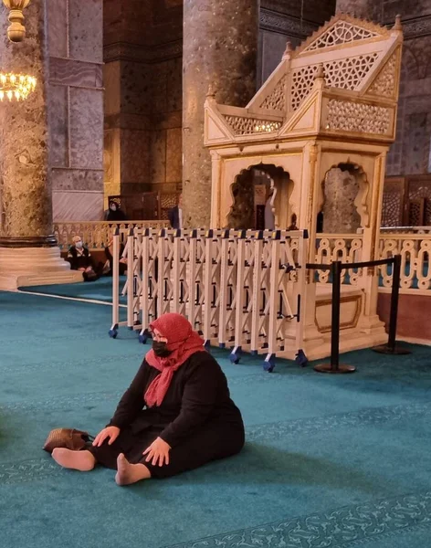   Siyah elbiseli bir kadın tapınakta yerde oturuyor.