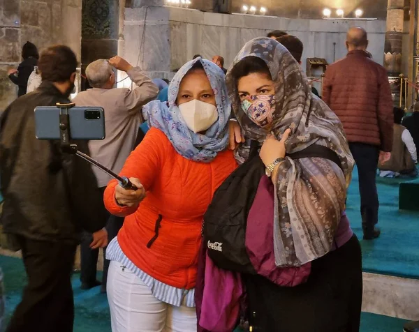 Maskeli kadınlar tapınakta selfie çekiyorlar.