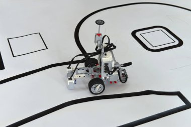 Kağıt yolda tekerlekleri olan programlanabilir robot. Engel çizgisi olan robotik araba yeteneğini takip et