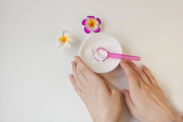 Bowl with white clay powder. womans hands on white. Ingredients for facial and body mask or scrub Stock Photo