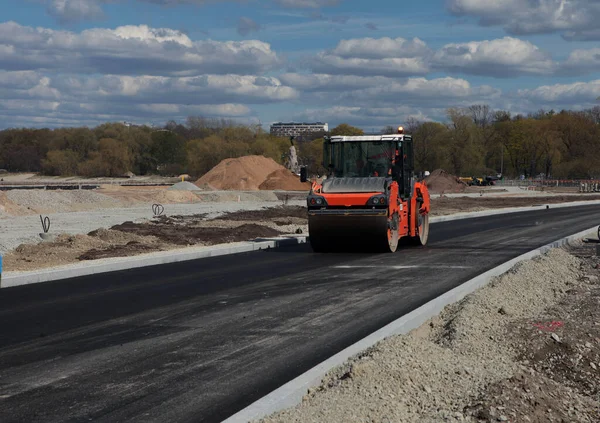 Roller rolling fresh hot asphalt on the new road. Road construction.