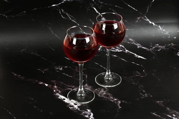 Two glasses with red wine on a dark background