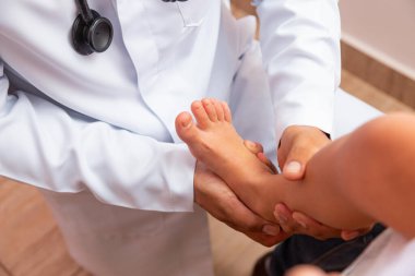 doctor examining children's feet in hospital. Surgeon, traumatologist or orthopedist palpating girl's leg and foot