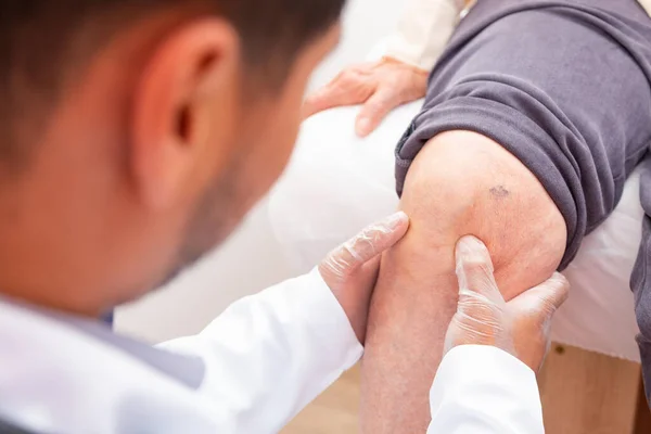 physiotherapist doctor examining, massaging and treating elderly patient knee and leg in orthopedic medical clinic nursing hospital.