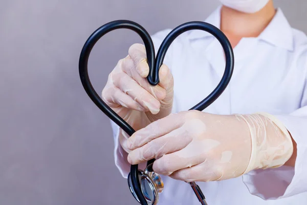Photo of nurse holding stethoscope on gray background