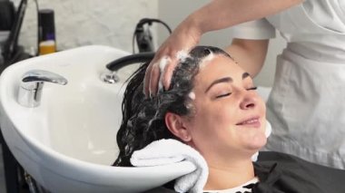 Kozmetik uzmanı ameliyatlar için kızın kafasını şampuanla yıkar. Siyah saçlı. artı boyut.