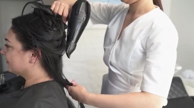 Güzellik uzmanı, müşteriye havlu ile kafasını kurutur. lavabo, siyah saç, artı beden.