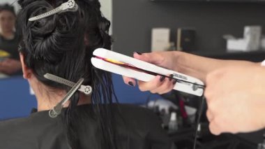 Kozmetik uzmanı hastanın saçını tedavi eder ve saçını da düzleştirir. Ultraviyole ışık kullanarak. Siyah saçlı. Artı boyut. Güzellik salonu