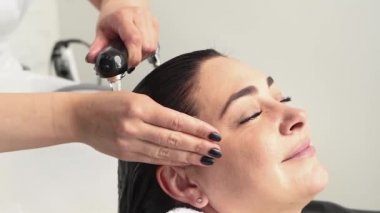 Kozmetik uzmanı ameliyatlar için kızın kafasını şampuanla yıkar. Siyah saçlı. artı boyut.