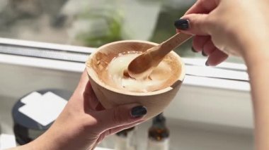 Güzellik uzmanı sarı saç maskesini ahşap tabakta karıştırıyor.