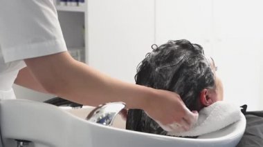 Kozmetik uzmanı ameliyatlar için kızın kafasını şampuanla yıkar. Siyah saçlı. artı boyut.