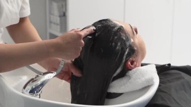 Kozmetik uzmanı ameliyatlar için kızın kafasını şampuanla yıkar. Siyah saçlı. artı boyut.
