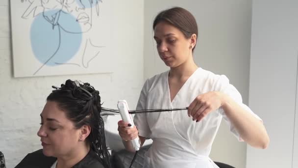 Κοσμητολόγος Θεραπεύει Μαλλιά Του Ασθενούς Και Επίσης Ισιώνει Μαλλιά Υπεριώδες — Αρχείο Βίντεο