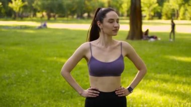Parktaki bir kız spor için arka planda mavi bir spor paspasın üzerinde mor bir bluzla spor yapmaya gidiyor. Bir çayır ve ağaçlar.
